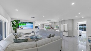Una sala de estar moderna con un amplio sofá modular, un televisor de pantalla plana y una mesa de centro de vidrio.