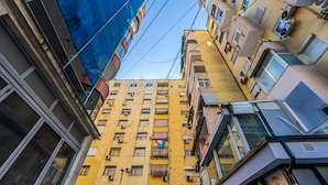 A multi-story building with balconies, air conditioning units, and a visible storefront. - 1 Bedroom Loft - Serenitas 1 (Tirana)