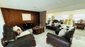 A living room with leather sofas, a coffee table, and a brick accent wall.