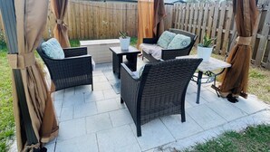 An outdoor patio with wicker furniture, a table, and potted plants.