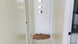 A narrow hallway with a marble floor, white walls, and a ceiling light fixture.
