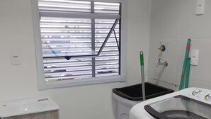 A laundry room with a window, a washing machine, a dryer, and a cabinet.