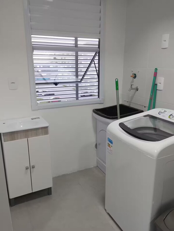 A laundry room with a window, a washing machine, a dryer, and a cabinet.