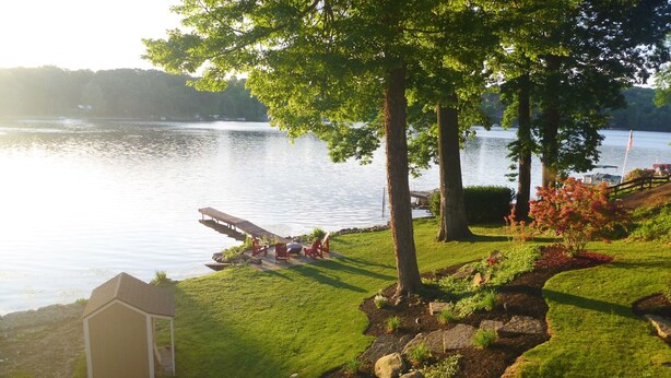 A lakeside garden with a wooden dock, a small shed, and a well-maintained lawn. - Portage Lakes, Lakefront, Private Dock & Deck (Akron)