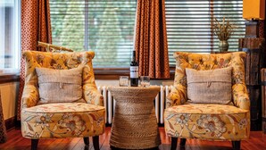 A room with two floral armchairs, a woven side table, and a bottle of wine. - Portage Lakes, Lakefront, Private Dock & Deck (Akron)