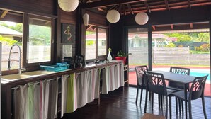 A wooden bar area with a counter, stools, and hanging paper lanterns. - Heipoe Lodge (Avera, Raiatea)