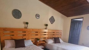 Una habitación con dos camas, cabeceros de madera, techo de madera y paneles decorativos en la pared.