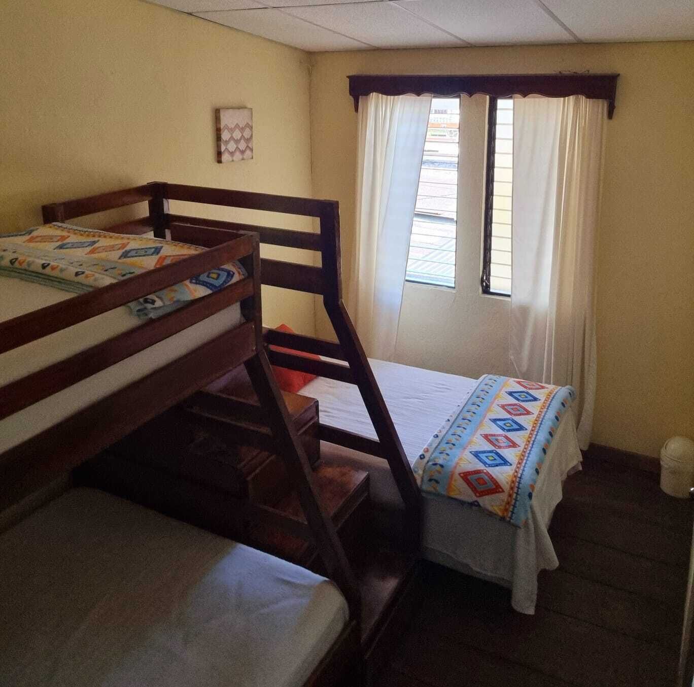 Un dormitorio con literas, una ventana con cortinas y un pequeño adorno en la pared.
