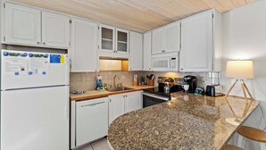 A kitchen with white cabinets, a granite countertop, a refrigerator, a microwave, and a coffee maker. - 5-Min Walk to Beach, Pet Friendly & Fire Pit (St. Augustine)