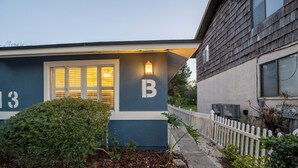 Ett hus med en stor bokstav ”B” på sidan, en välskött trädgård och ett vitt staket.