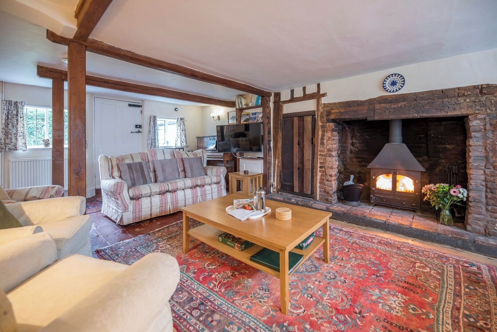 A cozy living room with a fireplace, a sofa, a coffee table, and a patterned rug.