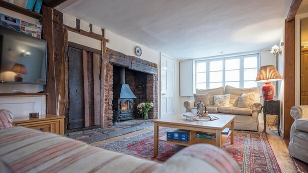 A cozy living room with a fireplace, a sofa, a coffee table, and a television. - Varley House, Saxmundham (Saxmundham)