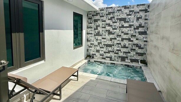 Ein moderner Poolbereich im Freien mit einer gefliesten Wand, einer Bank und einem Tisch.