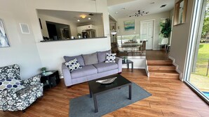 A modern living room with a grey sofa, patterned armchair, and a coffee table. - Riverfront Home in Houston with private pool and hot tub (Houston)