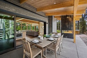 Un espace de restauration en plein air avec une longue table en bois, dressée pour quatre personnes, entourée de chaises en bois.