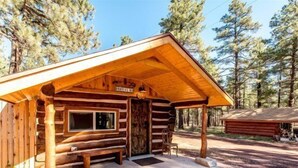 A log cabin with a wooden porch, a bench, and a door.