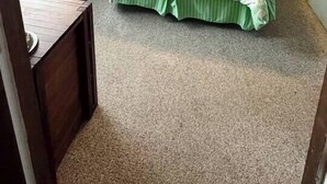 Un dormitorio con cama, dos lámparas de noche, un ventilador de techo, una ventana con persianas y un escritorio pequeño.