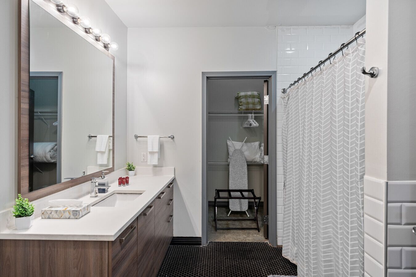 Bathroom with vanity mirror, shower tub combo, and connected walk-in closet with ironing amenities.