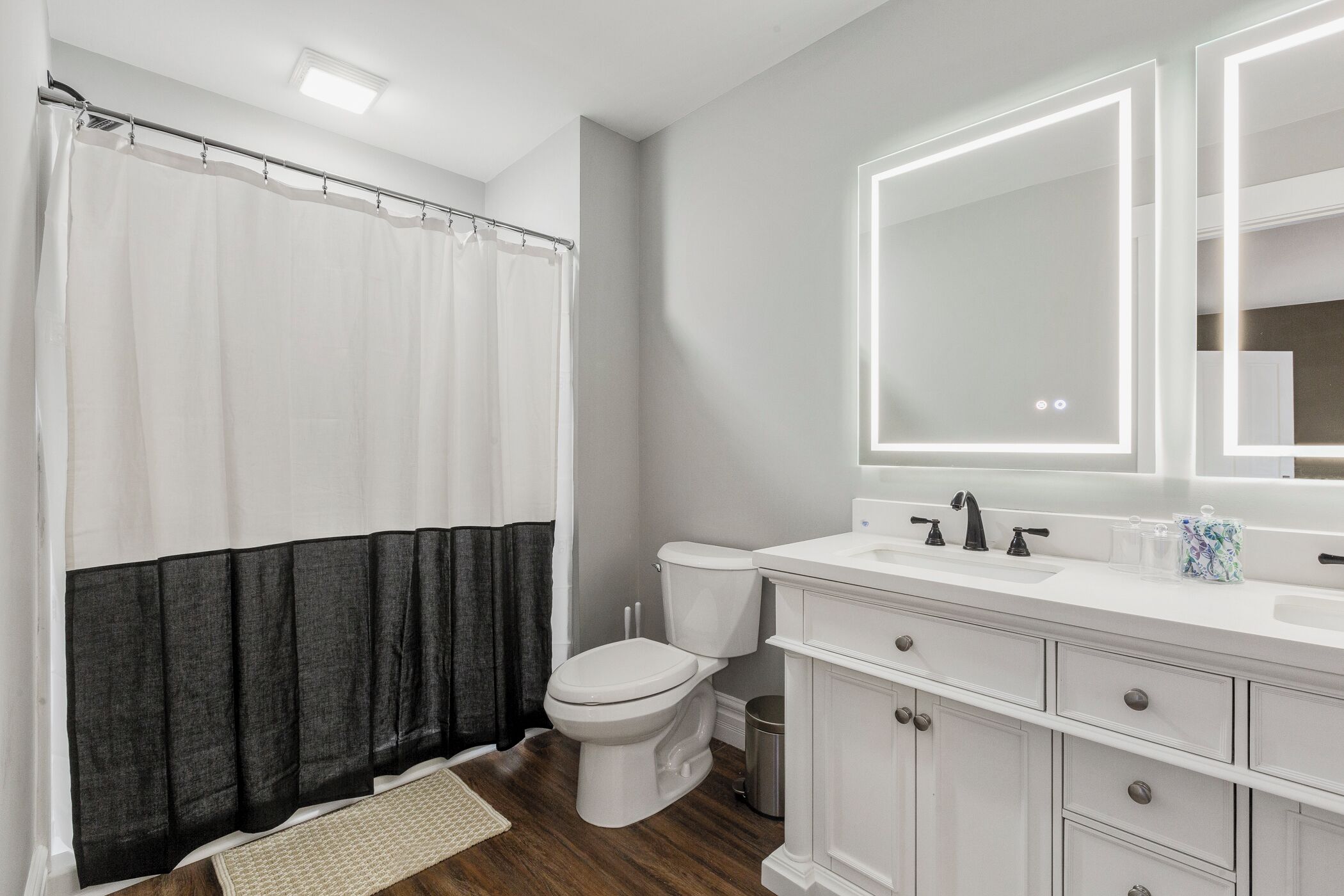 Ein modernes Badezimmer mit Duschvorhang, Toilette, Waschbecken und Waschtisch.