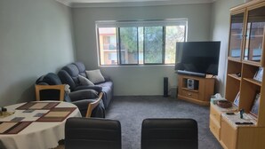 A living room with a sofa, TV, and a dining table. -  Bribie Island Dreams (Bongaree)