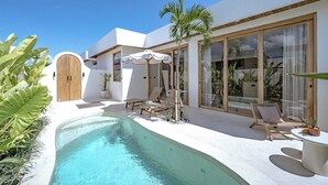 Ein modernes Haus mit Swimmingpool, Sitzgelegenheiten im Freien und großen Fenstern.
