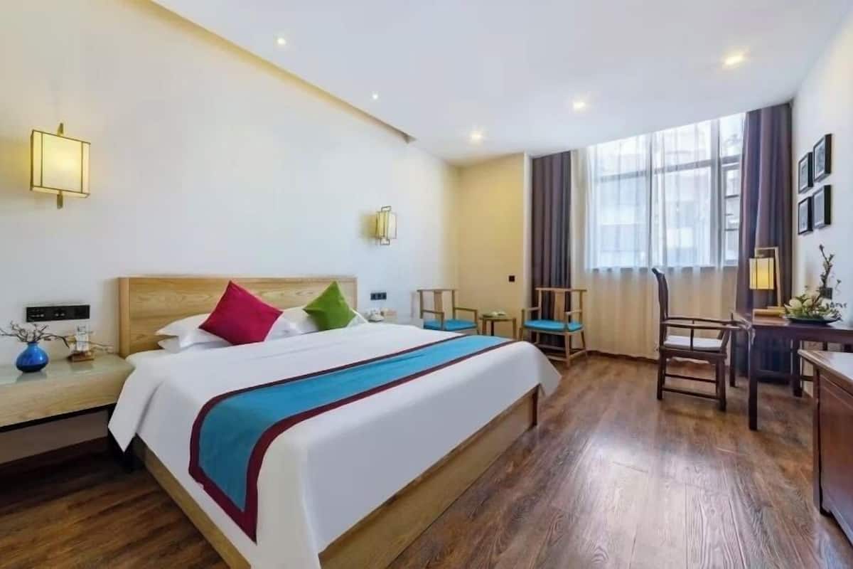 A hotel room with a large bed, bedside tables, a desk, and a chair.