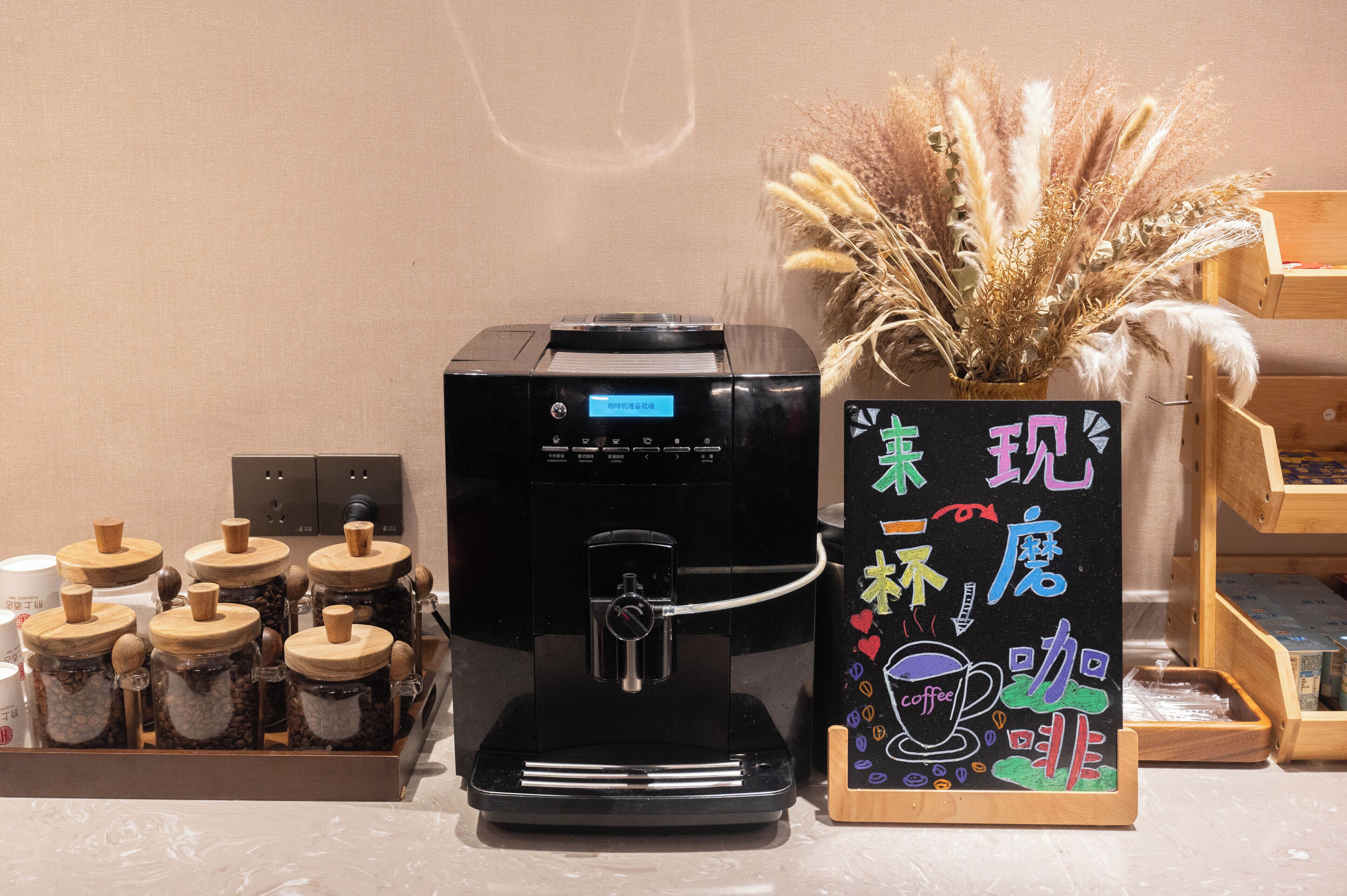 Una cafetera, un cartel con caracteres chinos y frascos de granos de café.
