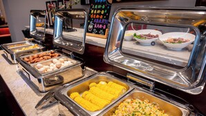 Ein Buffet mit verschiedenen Speisen, darunter Mais, Eier und Reis.