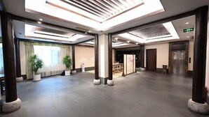 Eine geräumige Lobby mit hoher Decke, großen Fenstern und einem Empfangsbereich.