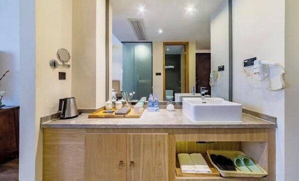Un baño moderno con un espejo grande, un lavabo, un secador de pelo y un perchero para toallas.