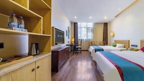 Ein Hotelzimmer mit zwei Betten, einem Schreibtisch, einem Fernseher und einer Minibar.