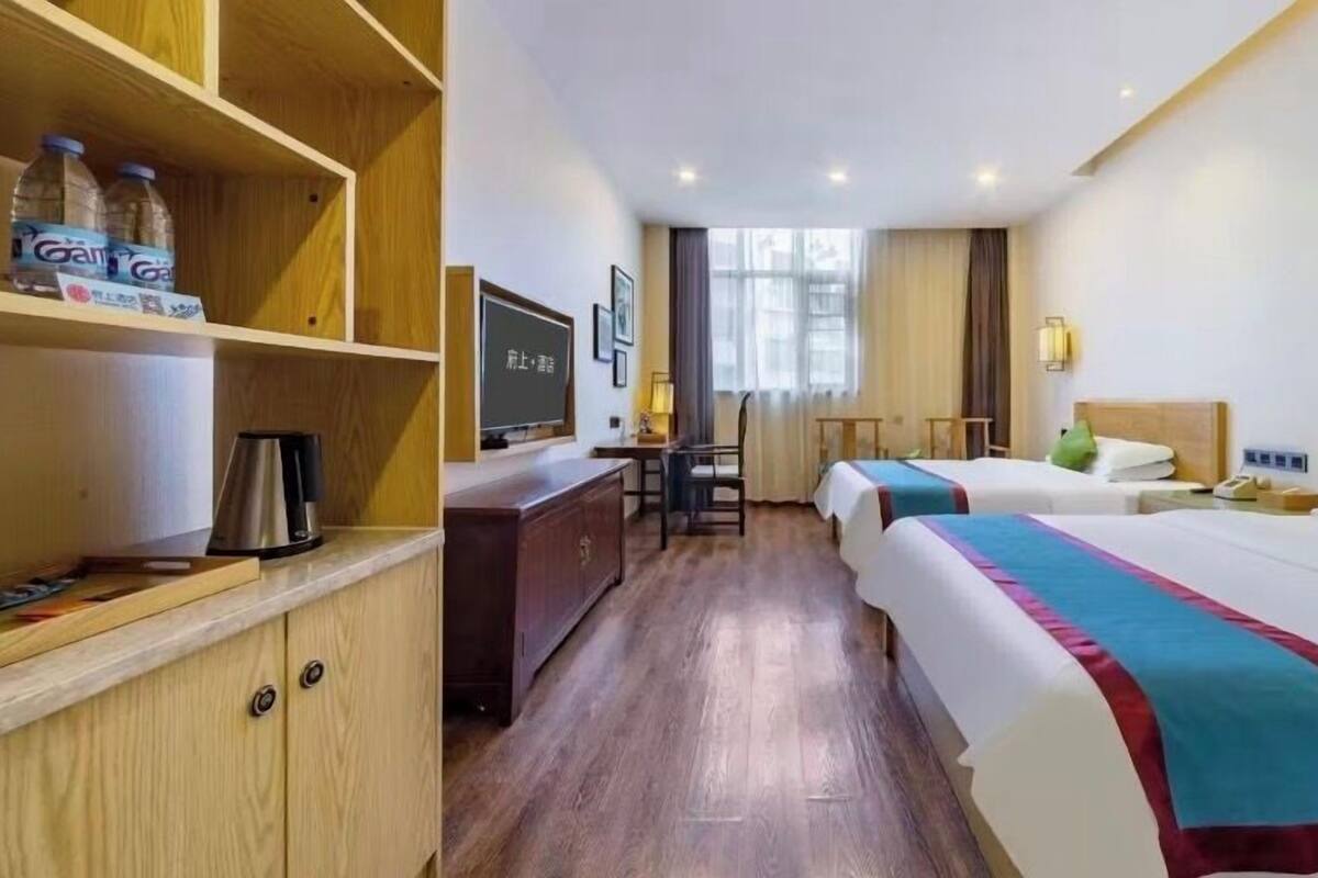 A hotel room with two beds, a desk, a television, and a minibar.