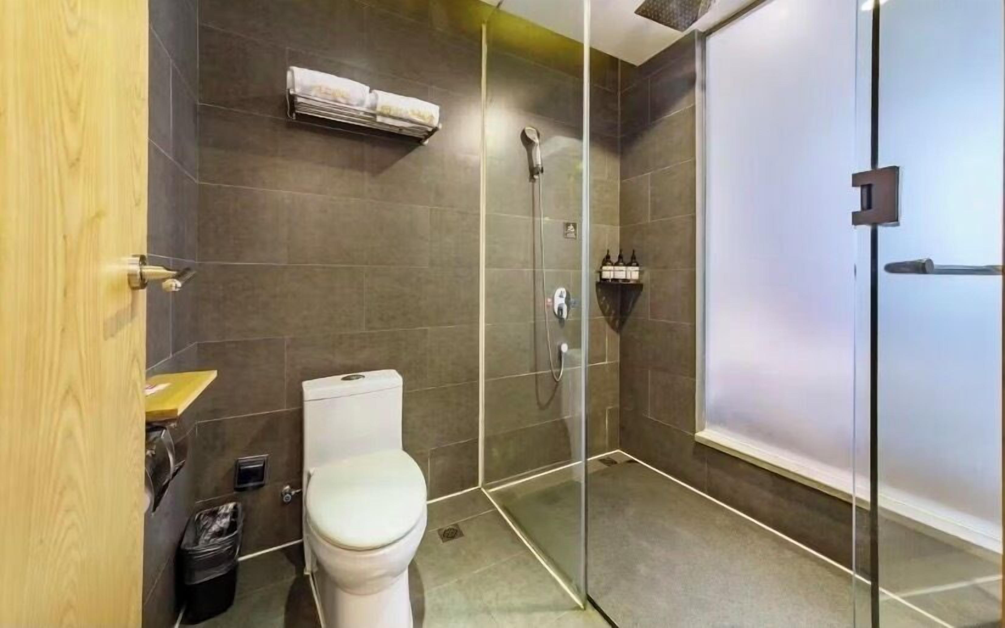 A modern bathroom with a toilet, a shower enclosure, and a glass door.