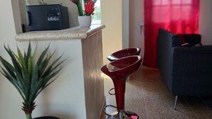 Eine moderne Küche mit Kühlschrank, einer Topfpflanze und einem roten Barhocker.