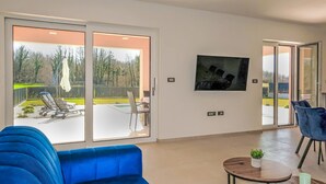 A modern living room with a blue sofa, a coffee table, and a TV mounted on the wall. - Villa Temelia by Interhome (Rovinj/Žminj)