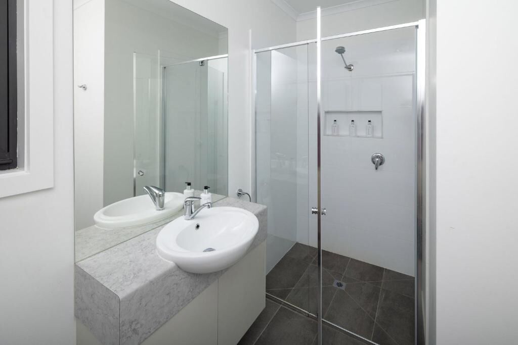 A modern bathroom with a glass-enclosed shower, a double sink vanity, and a large mirror.