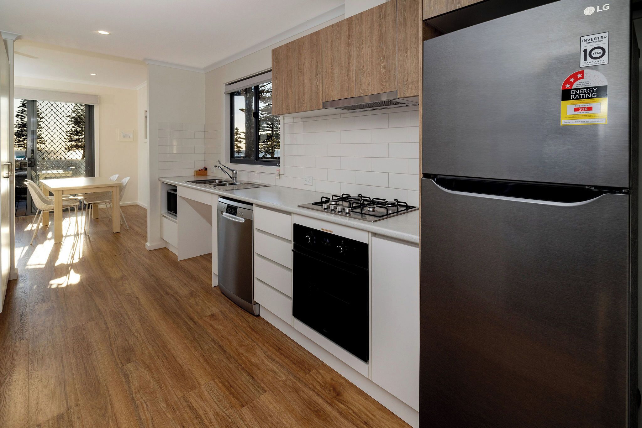 A modern kitchen with white cabinets, a stainless steel refrigerator, a gas stove, and a dishwasher.