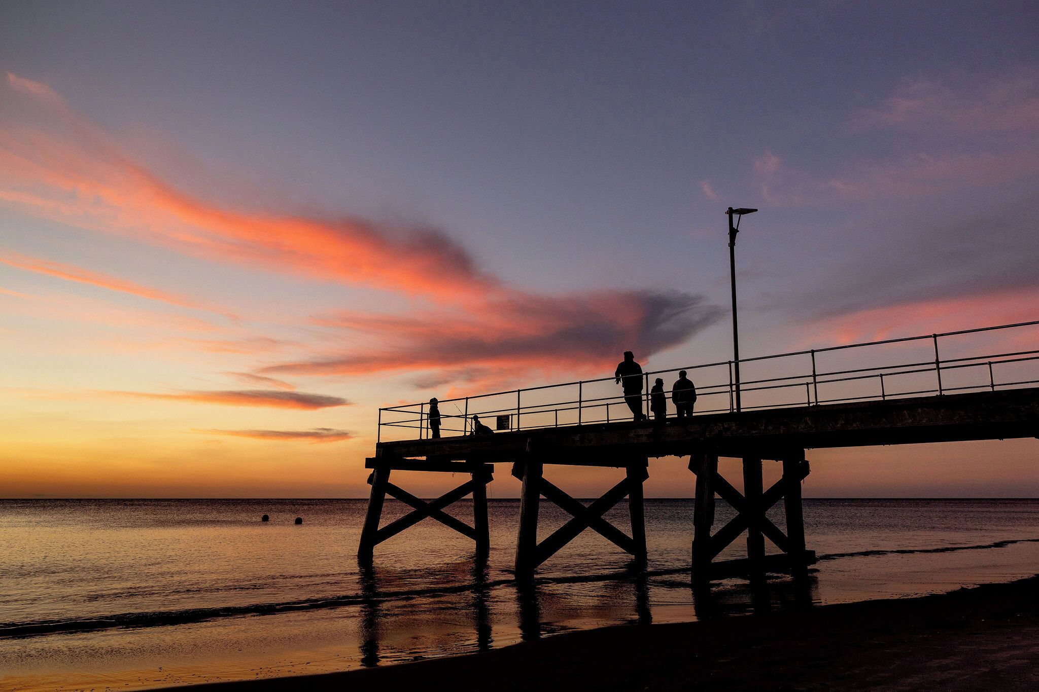 A pier extending into the water with people standing on it.