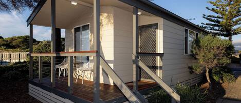 A modern house with a deck, outdoor seating, and a staircase leading to the entrance.