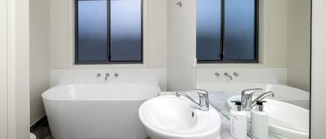 A modern bathroom with a freestanding bathtub, a sink, and a large mirror.