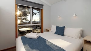 Una habitación de hotel con cama, ventana con vistas, una mesita y una silla.