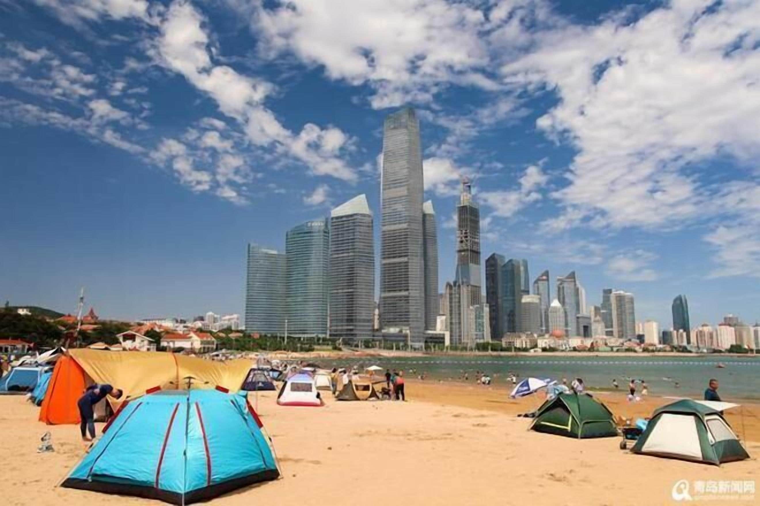 A beach with tents and a city skyline in the background.