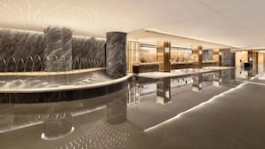 Een moderne lobby met een marmeren receptiebalie, een zithoek en een grote spiegel.