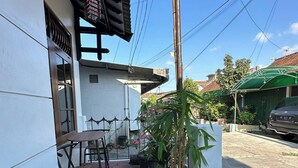 Eine Terrasse mit Tisch und Stühlen, umgeben von Blumentöpfen und einem kleinen Garten.