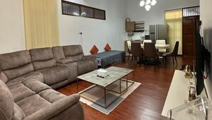 Ein modernes Wohnzimmer mit einer Eckcouch, einem Couchtisch und einem Essbereich mit Tisch und Stühlen.