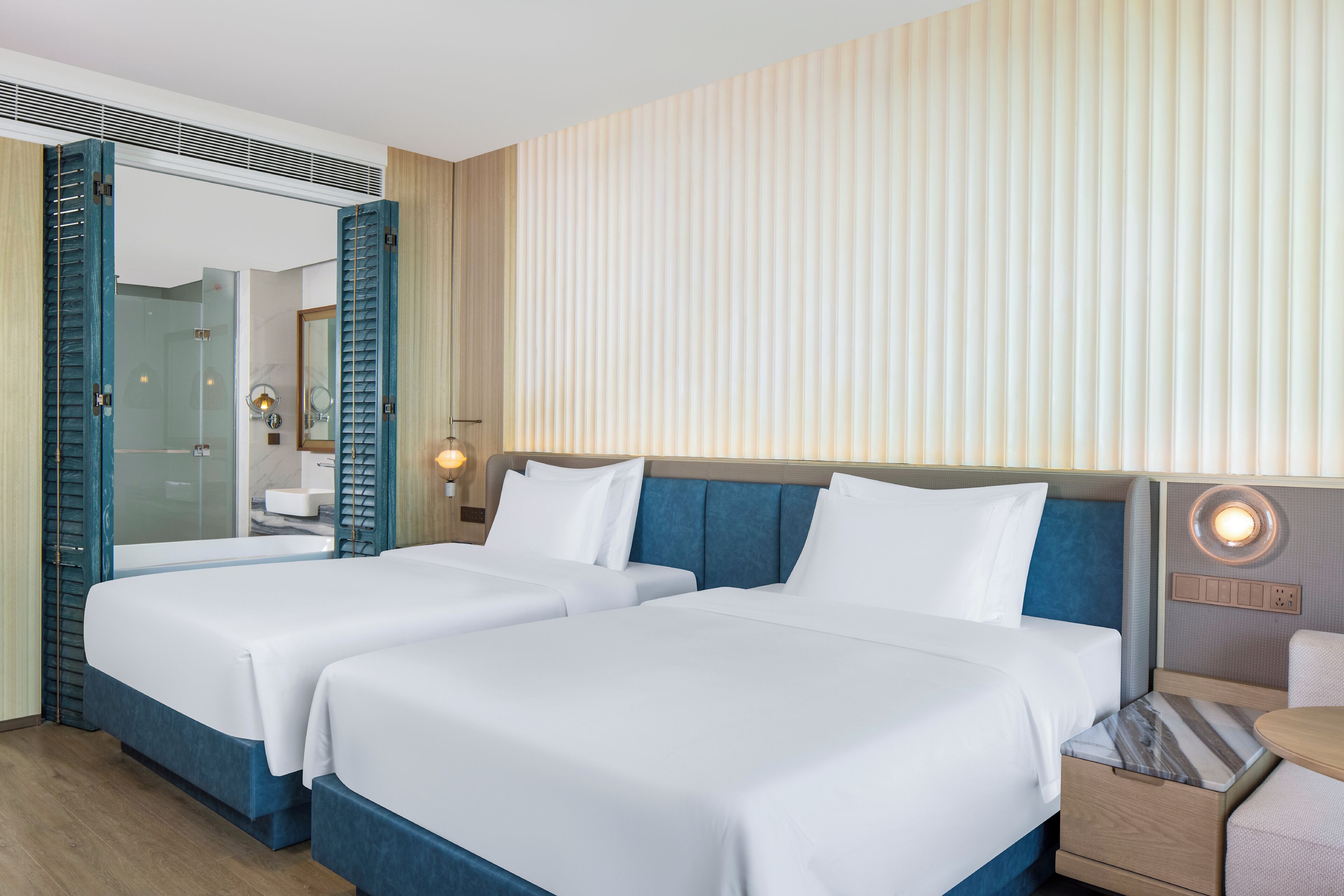 A hotel room with two beds, a bathroom, and a seating area.