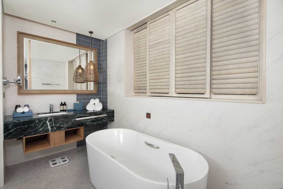 A modern bathroom with a freestanding bathtub, a large mirror, and a vanity with a marble countertop.