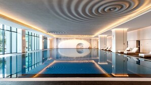 Ein moderner, überdachter Pool mit außergewöhnlichem Deckenstil, großen Fenstern und Liegebereichen.