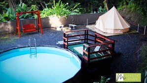 A backyard with a swimming pool, a swing set, a tent, and a small deck with chairs. - Mystic River Retreat | 3BR/2BA•Pool - Jacuzzi - Beverly Hills, Guaynabo, Guaynabo, Puerto Rico (Guaynabo)