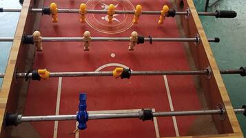A foosball table with a red playing surface and multiple rods with figures.